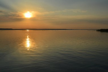 Sahilde yükselen güneşi olan bir fener..
