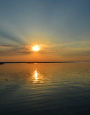 Sahilde yükselen güneşi olan bir fener..