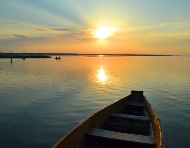 Sahilde yükselen güneşi olan bir fener..