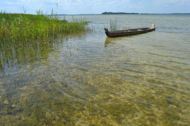Huş ağacından bir göle bağlı basit ahşap bir teknesi olan güzel bir manzara. Doğada güzel bir yaz günü. Gölde tatil kavramı. Pankart.