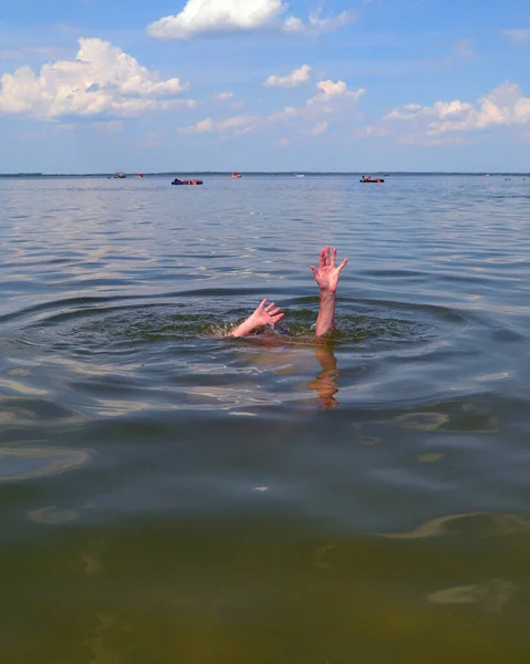 Hands of a drowning man above water in need of help.