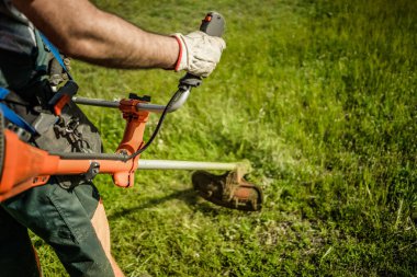 Güneşli bir bahar gününde bahçede çim biçme makinesiyle çimleri buduyor. Perspektif görünümü