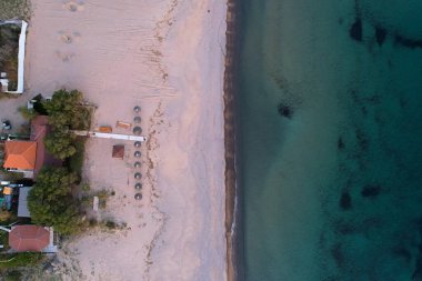 Şemsiyeli kumlu kumlu sahil manzarası ve limnos adasındaki turkuaz su.