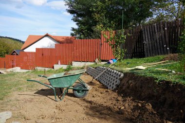 Romanya seyahati. Tranilvania Targu, inşaat halindeki bir bahçe duvarının yanında toprak ve el arabası taşıyor.