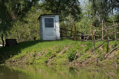 Romanya 'ya seyahat et. Sülsea sulina danube delta Karadeniz taşralı ahşap kulübe sakin suyun yanında yeşil yaprakları yansıtıyor.