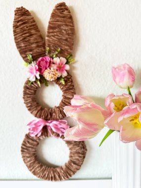 Çiçekli tavşan çelengi yanında pembe laleler Narin taç yaprakları ve ipek desenli yumuşak odak kompozisyonu