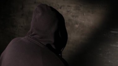 Karanlık bir istasyon odasında polis sorgusu sırasında kameraya geri dönen isimsiz bir kapüşonlu hacker. Siber suçlar soruşturması, kanun uygulama sorgulaması, gizlilik.