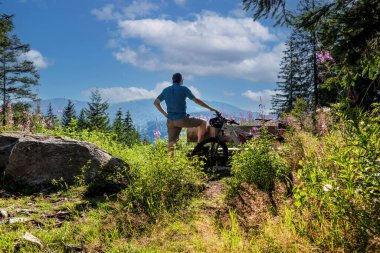 Bisikletçi, Kara Orman 'daki Feldberg dağına bakan bir bankta mola veriyor.
