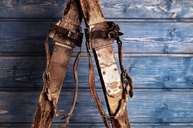 Mavi ahşap arka planda deri kayaklarla bağlanmış antik ahşap kayaklar.