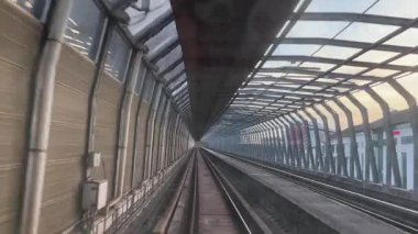 Kuala Lumpur 'dan geçen rayları gösteren yüksek bir trenin görüntüsü. ELM İşletme Fakültesi 'ne ev sahipliği yapan HELP Üniversitesi binası, altın saat gökyüzünün altında kırmızı çatıyla görülebiliyor. Demiryolu boyunca bir ses bariyeri var..