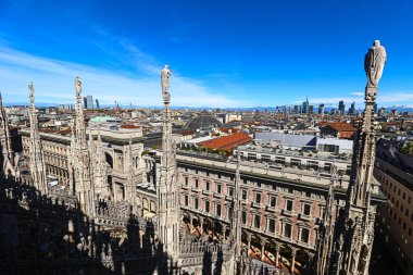 Duomo di Milano 'nun çatısı üzerindeki yüksek açılı panoramik manzara, İtalya' nın Milano kentinin yoğun siluetine, parlak mavi gökyüzünün altına bakıyor..