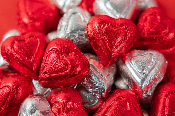 Bir yığın kırmızı ve gümüş folyo paketlenmiş çikolata şekeri.