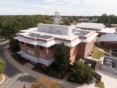 Büyük bir fotovoltaik güneş paneli dizisi içeren Apex Town Hall çatısının havadan görüntüsü. Beyaz düz çatı, 