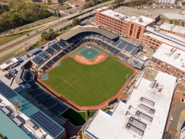 Güneşli bir öğleden sonra Durham Bulls Atletizm Parkı 'nın yüksek açılı görüntüsü. Atış yeşil dış saha, muşamba kaplı bir iç saha ve şehir merkezindeki tuğla binalar ve bir otoyol arasına kurulmuş stadyumu gösteriyor..