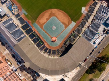 Durham Bulls Atletizm Parkı 'nın iç saha görüntüsü. Beyzbol elması büyük yeşil bir muşambayla kaplıdır, koyu renkli stadyum koltukları, gri metal bir çatı ve bitişik çok şeritli bir yol ile çerçevelenmiştir..