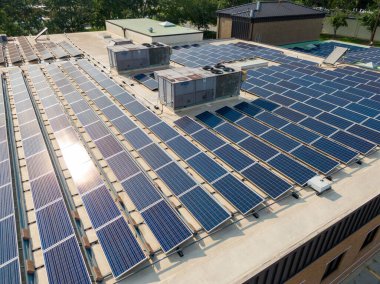 Uçsuz bucaksız ticari çatı güneş panelinin hava perspektifi. Düz endüstriyel yüzey boyunca geniş HVAC birimleri ve temiz enerji üretimi için havalandırma sistemleri ile birleştirilmiş birçok sıra mavi fotovoltaik paneller monte edilmiştir..