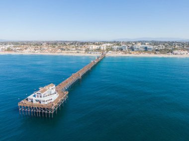 Derin mavi Pasifik 'e uzanan tarihi Okyanus Kıyısı' nın büyüleyici hava manzarası. Yangından önce, uzun ahşap yapı tam olarak ayakta duruyor, arka planda canlı Güney Kaliforniya kıyı şeridi olan son binaya gidiyor..