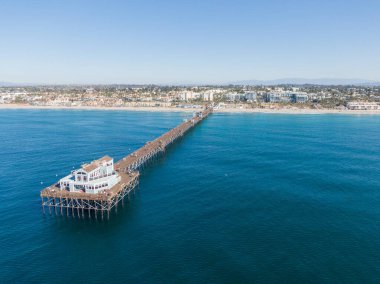Derin mavi Pasifik 'e uzanan tarihi Okyanus Kıyısı' nın büyüleyici hava manzarası. Yangından önce, uzun ahşap yapı tam olarak ayakta duruyor, arka planda canlı Güney Kaliforniya kıyı şeridi olan son binaya gidiyor..