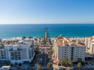 Batıya, Okyanus Kıyısı ve Pasifik Okyanusu 'na bakan bir hava manzarası. Sahne, kıyı tatil beldeleri, palmiyeli kaldırımlar ve engin mavi gökyüzünün altında kıyıya uzanan şehir plazalarını gösteriyor..