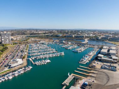 Okyanus kıyısındaki panorama yelkenli ve yatlarla dolu. Manzarada limanın sakin turkuaz suyu, ikonik deniz feneri ve uzaktaki Oceanside İskelesi ile San Luis Rey Nehri 'ni geçen bir köprü yer alıyor..