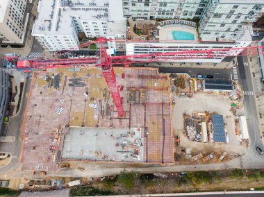 Yüksek açılı bir hava perspektifi, Raleigh 'in North Hills bölgesindeki bir inşaat alanını yakalıyor. Park Central apartmanının bitişiğindeki çok katlı beton bir otoparkın üzerinde uzun kırmızı bir vinç duruyor..