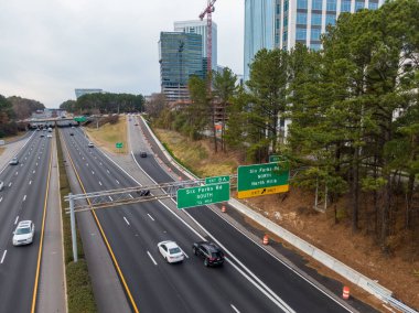 Geniş açılı insansız hava aracı Raleigh 'in North Hills bölgesindeki Six Forks Road kavşağında I-440 Beltline gösteriyor. Çekim, yüksek binalar, etkin inşaat vinçleri ve otoyolda uzanan yeşil çam ağaçlarını yakalıyor..