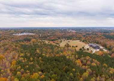 Bu geniş dron fotoğrafı Wake Forest, Kuzey Carolina 'nın nefes kesici sonbahar manzarasını yakalar. Yoğun orman örtüsü, Joyner Park 'ı çevreleyen parlak turuncu ve sarı sonbahar yapraklarıyla dönüşür. Seyahat ve turizm için mükemmel..