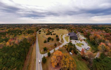 Bu geniş dron fotoğrafı Wake Forest, Kuzey Carolina 'nın nefes kesici sonbahar manzarasını yakalar. Yoğun orman örtüsü, Joyner Park 'ı çevreleyen parlak turuncu ve sarı sonbahar yapraklarıyla dönüşür. Seyahat ve turizm için mükemmel..