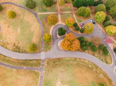 Bu doğrudan yukarıdaki dron çekimi Wake Forest, Kuzey Carolina 'da sonbahar renklerinin çarpıcı bir duvar halısını yakalıyor. Kuş bakışı perspektifi, Joy Park 'ın en yüksek sonbahar sezonundaki canlı turuncu ve sarı örtüsünü vurguluyor..