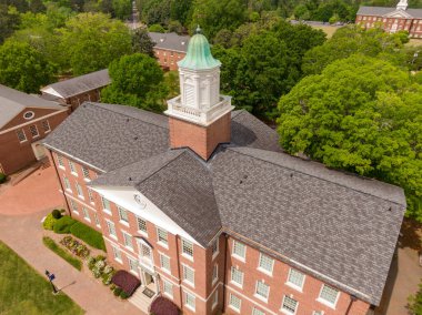 Wake Ormanı 'ndaki tarihi tuğladan kilisenin çarpıcı hava manzarası. Çekim, çok gagalı asfalt çatının, bakır kubbeli süslü beyaz kubbenin ve çevresini saran yemyeşil kampüs yeşilliğinin simetrik karmaşıklığını yakalar..