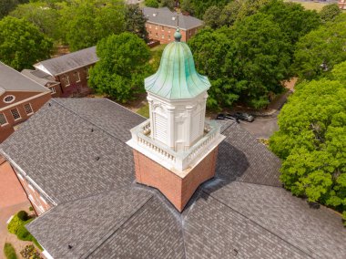 Wake Ormanı, NC 'deki Binkley Şapeli kubbesine yakın çekim. Çekim, kubbenin yıpranmış bakır tabakasını, beyaz mimari çerçeveyi ve etrafındaki dik katlı çatıdaki asfalt kiremitlerin hassasiyetini vurguluyor..