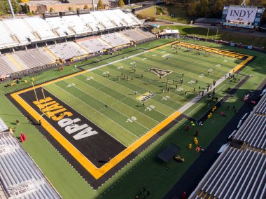 Kidd Brewer Stadyumu 'ndaki yüksek insansız hava aracı atışı, Appalachian Eyalet Üniversitesi futbol takımını sahada sergiliyor. Kaya olarak bilinen siyah ve altın çim bu Boone, Kuzey Carolina 'nın odak noktasıdır..