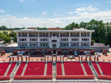 Bu hava çekimi Carter-Finley Stadyumu 'nun kuzey ucu duvarını yakalıyor, NC State' in maç tarihini gösteren beyaz metin yer alıyor. Manzara kırmızı oturma sıralarını, beton stadyum yapısını ve Raleigh 'deki boş araziyi gösteriyor..