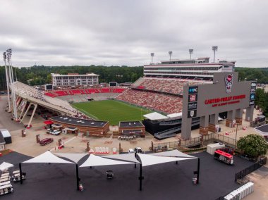 Carter-Finley Stadyumu ve Raleigh 'deki Lenovo Center arenasını gösteren geniş bir hava manzarası. Atış, futbol stadyumlarının iç saha arenası ve etrafındaki park alanlarının yanındaki bowling sahasını da kapsıyor..