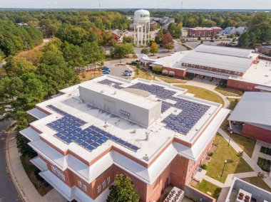 Apex, NC 'de geniş bir güneş paneli dizisi ve beyaz TPO zarının yer aldığı karmaşık bir ticari çatının havadan görüntüsü. Çekimde profesyonel kurulum, enerji verimliliği ve müteahhitler ve güneş enerjisi kurucuları için çağdaş altyapı vurgulandı.