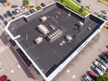 Siyah EPDM ya da modifiye edilmiş zarı olan büyük bir ticari düz çatının yüksek açılı hava görüntüsü. Çekimde, endüstriyel bakım ve mekanik kurulumlar için mükemmel olan birden fazla çatı HVAC birimleri ve yoğunlaştırıcı bankalar yer alıyor..