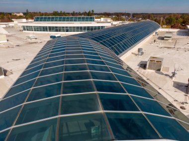 Bu hava aracı görüntüsü, bir membran çatıya entegre edilmiş büyük ölçekli ticari cam atriyum sistemine sahiptir. Raporda mimari cilalama ve modern tesislerdeki su geçirmez gündüz aydınlatması için gerekli teknik mühür vurgulanıyor.