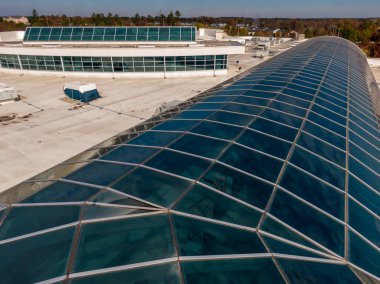 Bu hava aracı görüntüsü, bir membran çatıya entegre edilmiş büyük ölçekli ticari cam atriyum sistemine sahiptir. Raporda mimari cilalama ve modern tesislerdeki su geçirmez gündüz aydınlatması için gerekli teknik mühür vurgulanıyor.