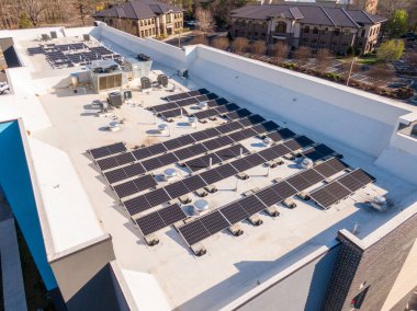 Büyük dengeli güneş paneli dizisi içeren beyaz bir TPO düz çatısının havadan görüntüsü. Gri metal kaplama, köşe drenajı ve temiz bir ticari kurulum üzerine küçük HVAC nüfuz duvarları içerir.
