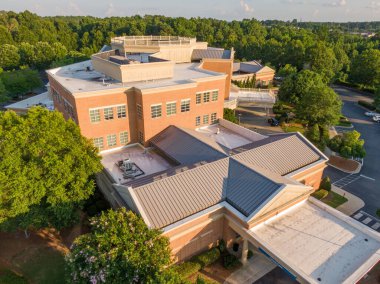 Bu hava aracı görüntüsünde bronzlaşmış, ayakta duran metal bir çatı klasik bir tuğla binayla buluşuyor. Yüksek açılı çekim, hassas doğrusal dikişler ve yıldırım koruma çubukları yakalar, profesyonel mimari metalleri vurgular ve dayanıklı koruma sağlar.
