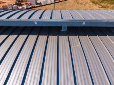 Bu hava aracı görüntüsünde modern bir ticari binanın gri, ayakta duran metal bir çatısı görülüyor. Temiz doğrusal tasarım ve entegre oluk sistemi, üst düzey perakende sahaları için profesyonel kurulum ve kalıcı mimari korumayı vurguluyor.