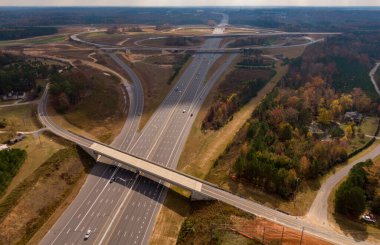 Bu hava çekimi Kuzey Carolina, Raleigh yakınlarındaki 40 numaralı otoban otobanındaki karmaşık türbin kavşağını gösteriyor. Karmaşık yol sistemi verimli Piedmont ormanları boyunca dokumakta, modern altyapıyı, yoğun trafiği ve bölgenin geniş çapını gözler önüne sermektedir..