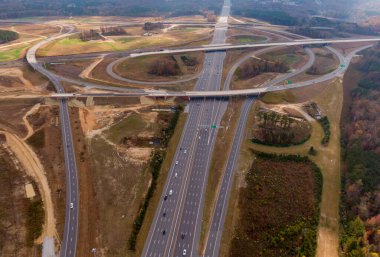 Bu hava çekimi Kuzey Carolina, Raleigh yakınlarındaki 40 numaralı otoban otobanındaki karmaşık türbin kavşağını gösteriyor. Karmaşık yol sistemi verimli Piedmont ormanları boyunca dokumakta, modern altyapıyı, yoğun trafiği ve bölgenin geniş çapını gözler önüne sermektedir..