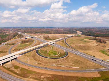 Bu hava çekimi Kuzey Carolina, Raleigh yakınlarındaki 40 numaralı otoban otobanındaki karmaşık türbin kavşağını gösteriyor. Karmaşık yol sistemi verimli Piedmont ormanları boyunca dokumakta, modern altyapıyı, yoğun trafiği ve bölgenin geniş çapını gözler önüne sermektedir..