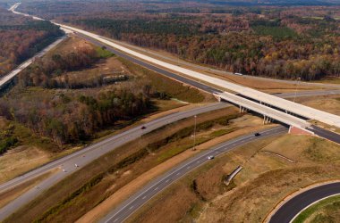 Bu hava çekimi Kuzey Carolina, Raleigh yakınlarındaki 40 numaralı otoban otobanındaki karmaşık türbin kavşağını gösteriyor. Karmaşık yol sistemi verimli Piedmont ormanları boyunca dokumakta, modern altyapıyı, yoğun trafiği ve bölgenin geniş çapını gözler önüne sermektedir..