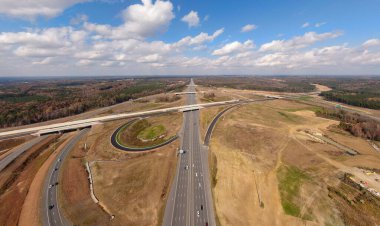 Bu hava çekimi Kuzey Carolina, Raleigh yakınlarındaki 40 numaralı otoban otobanındaki karmaşık türbin kavşağını gösteriyor. Karmaşık yol sistemi verimli Piedmont ormanları boyunca dokumakta, modern altyapıyı, yoğun trafiği ve bölgenin geniş çapını gözler önüne sermektedir..