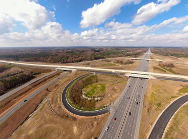 Bu hava çekimi Kuzey Carolina, Raleigh yakınlarındaki 40 numaralı otoban otobanındaki karmaşık türbin kavşağını gösteriyor. Karmaşık yol sistemi verimli Piedmont ormanları boyunca dokumakta, modern altyapıyı, yoğun trafiği ve bölgenin geniş çapını gözler önüne sermektedir..