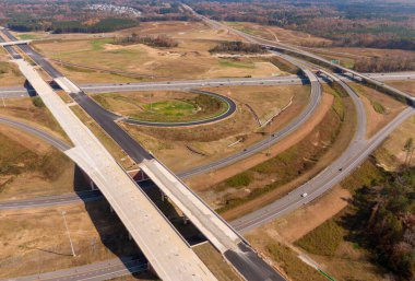 Bu hava çekimi Kuzey Carolina, Raleigh yakınlarındaki 40 numaralı otoban otobanındaki karmaşık türbin kavşağını gösteriyor. Karmaşık yol sistemi verimli Piedmont ormanları boyunca dokumakta, modern altyapıyı, yoğun trafiği ve bölgenin geniş çapını gözler önüne sermektedir..