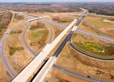 Bu hava çekimi Kuzey Carolina, Raleigh yakınlarındaki 40 numaralı otoban otobanındaki karmaşık türbin kavşağını gösteriyor. Karmaşık yol sistemi verimli Piedmont ormanları boyunca dokumakta, modern altyapıyı, yoğun trafiği ve bölgenin geniş çapını gözler önüne sermektedir..