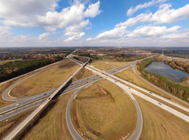Johnston County, NC 'deki Interstate 40 ve Interstate 95 kavşağının hava aracı görüntüsü. Karmaşık otoyol sisteminde geniş kıvrımlar, yoğun trafik ve sonbahar yaprakları yer alıyor ve bu da Doğu Yakası 'ndaki ana ulaşım arterini gösteriyor..
